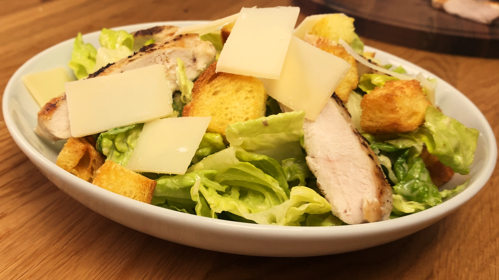 Classic Caesar salad with sliced grilled chicken, romaine lettuce, croutons, and parmesan on a plate.