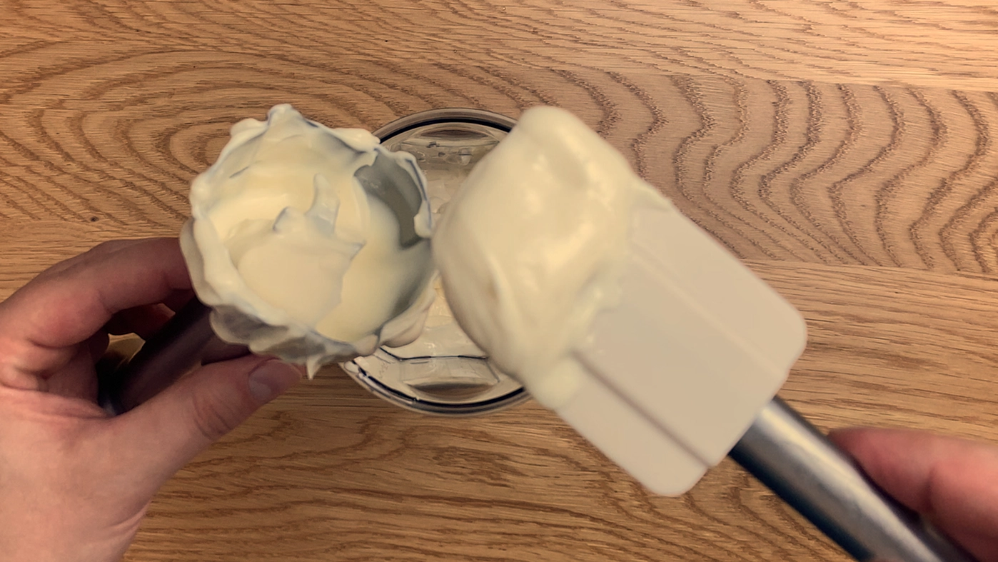 No-egg mayonnaise in a jar with creamy texture on spoon.