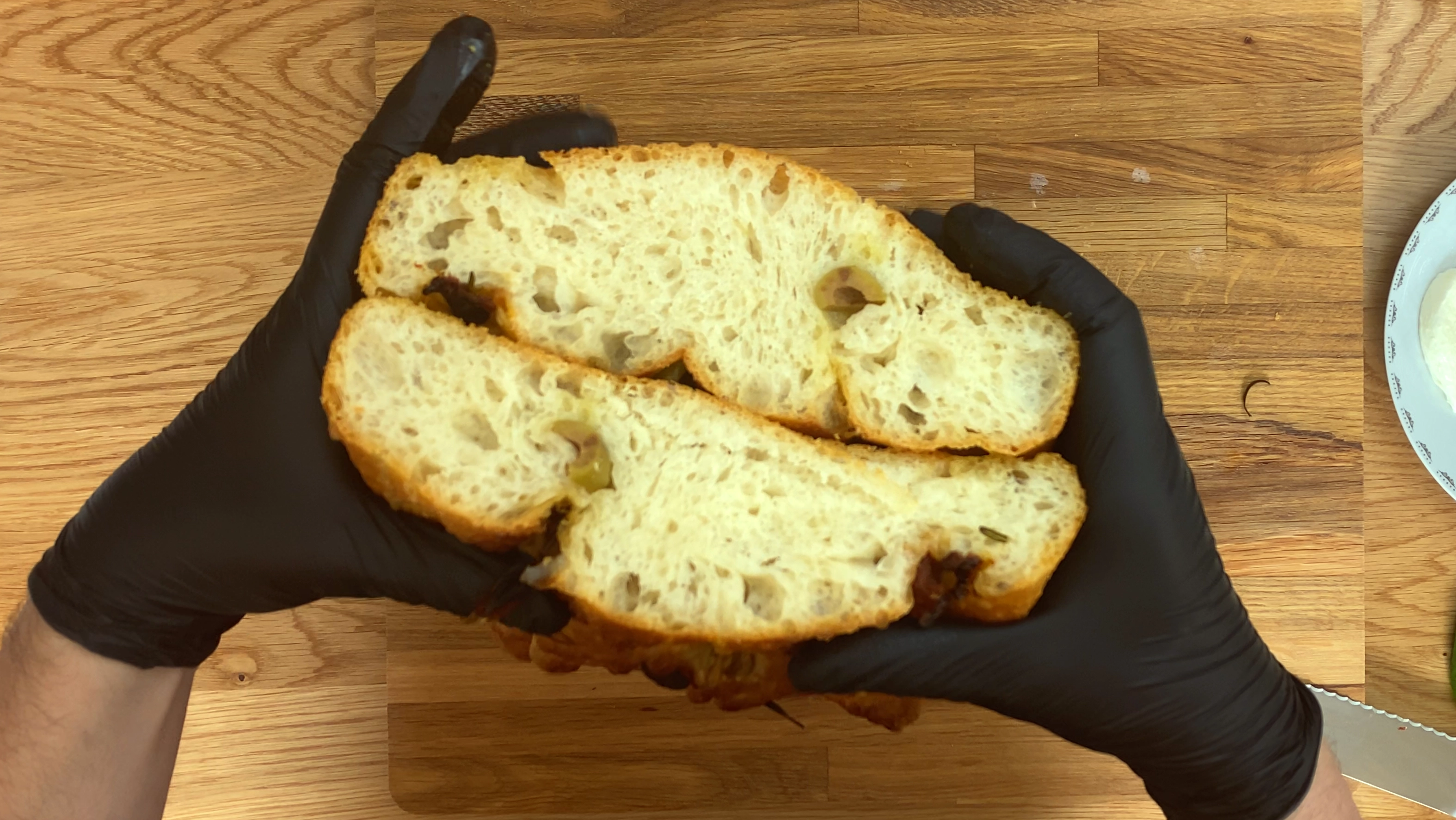 Golden, airy focaccia with a crisp crust, dimpled surface, and herb or topping details visible on top.